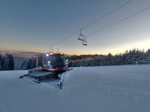Rolba na sjezdovce za soumraku pod lanovkou